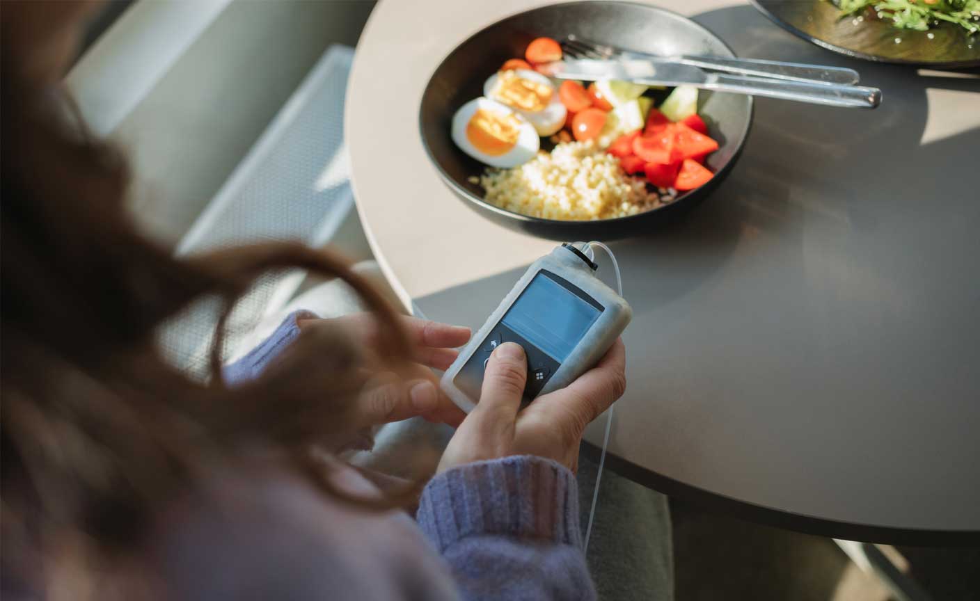 Woman in front of breakfast looking at insulin machine