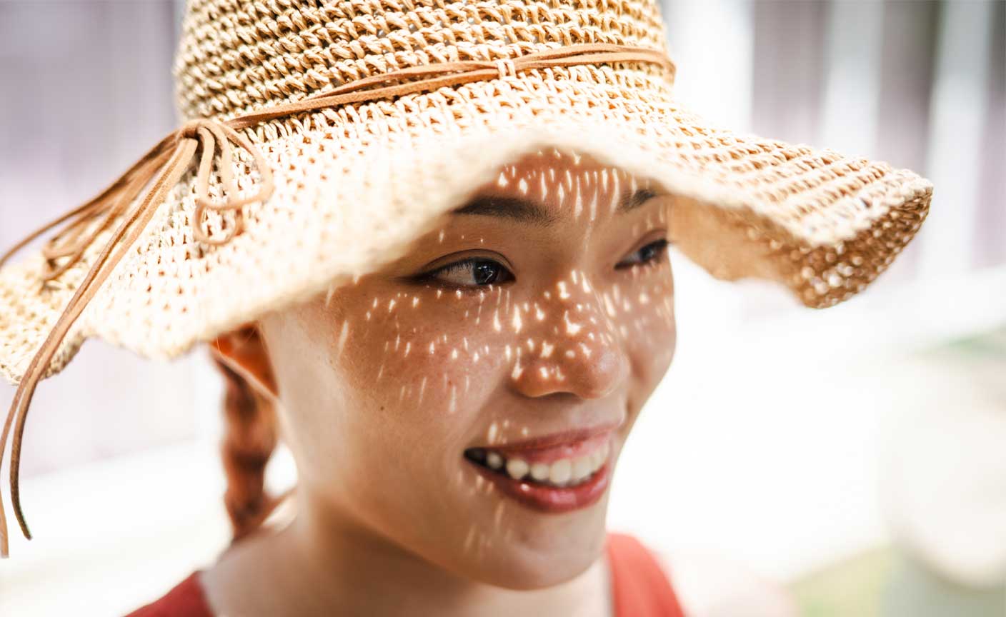 Smiling woman wearing a big hat outdoors