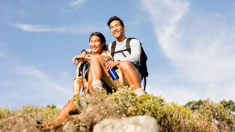 Two people take a break from hiking and sit on some rocks.