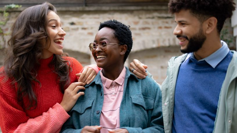 Three friends smiling while enjoying conversation together