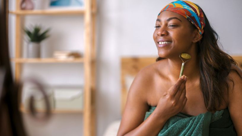 Young woman uses a face roller.