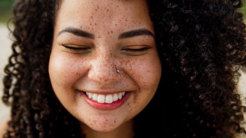 Young woman with freckles smiling.