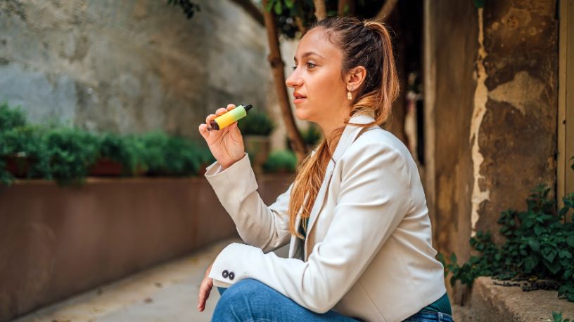 Young woman sitting down and vaping.