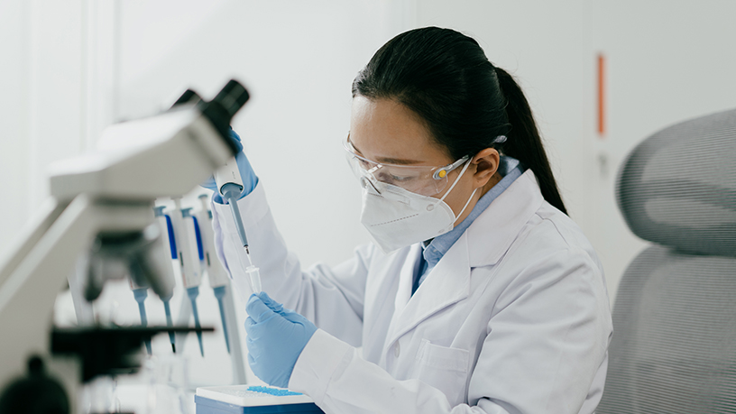 A women in a laboratory working on chemistry under a microscope.