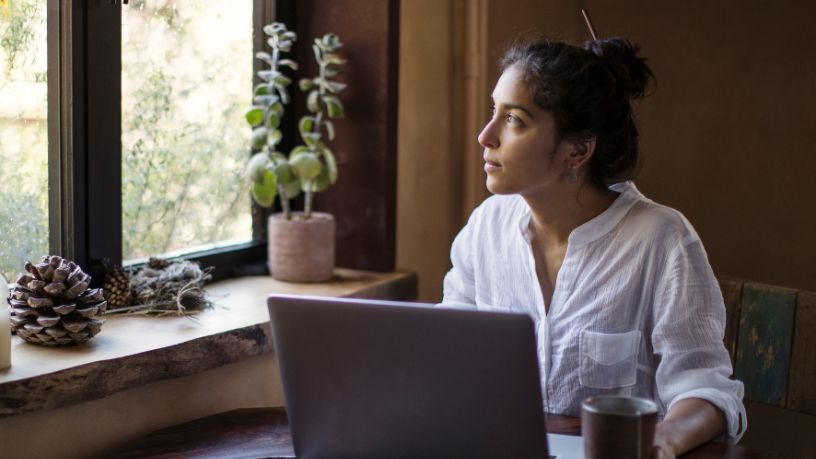 A woman looks pensively out her window.