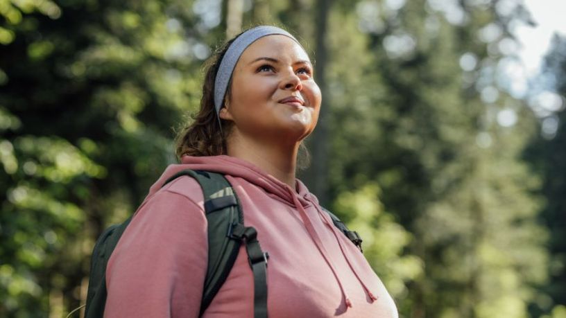A woman stands outside looking into the distance.