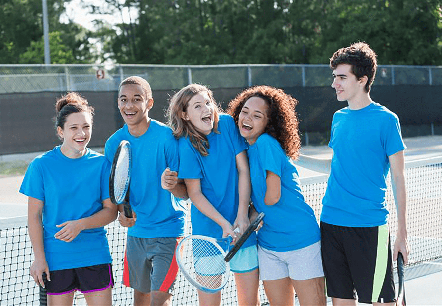 Children wearing blue sports uniforms smiling and standing together on an outdoor court, promoting inclusive sport for all abilities.