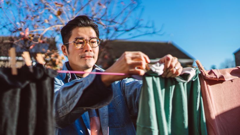 A man hangs clothes to dry on a clothesline.