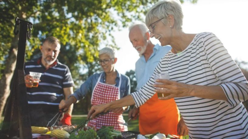 A group of friends in their 60s BBQ vegetables.