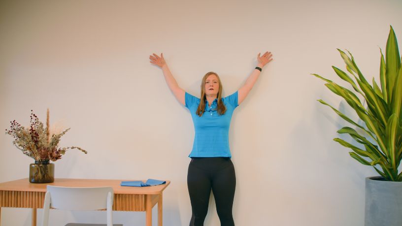 Bupa physio performing shoulder stretches against a wall