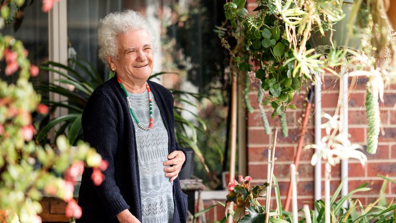 An older woman enjoys the sunshine in her garden.