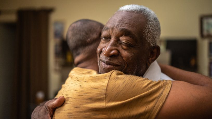 Two men hug and hold each other tightly.