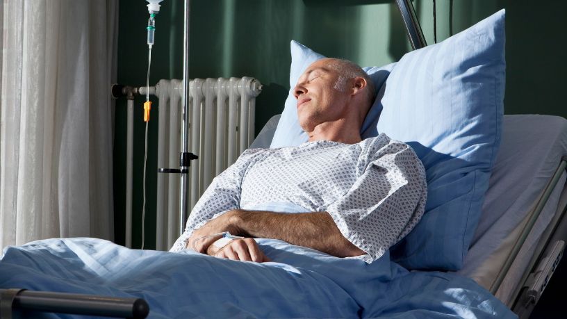 A man sleeps in a hospital bed.