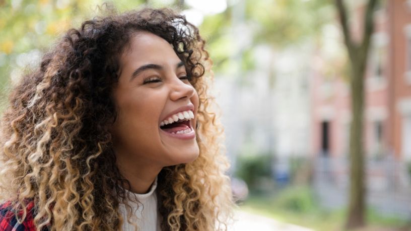 A woman laughs with her eyes closed.