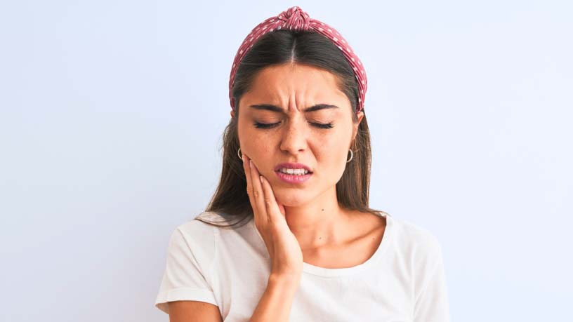 A woman rubs her sore jaw.