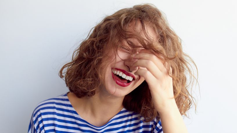 A woman sitting with her friends leans forward and smiles