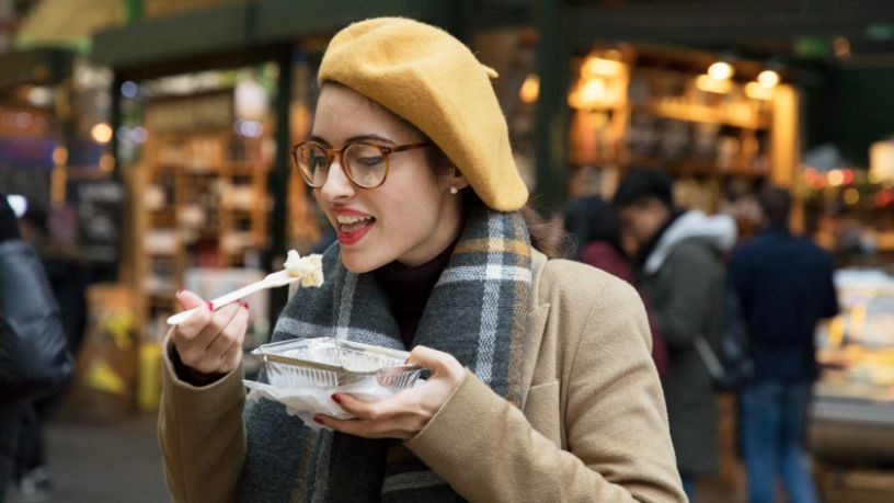 A woman eats food from a takeaway container.