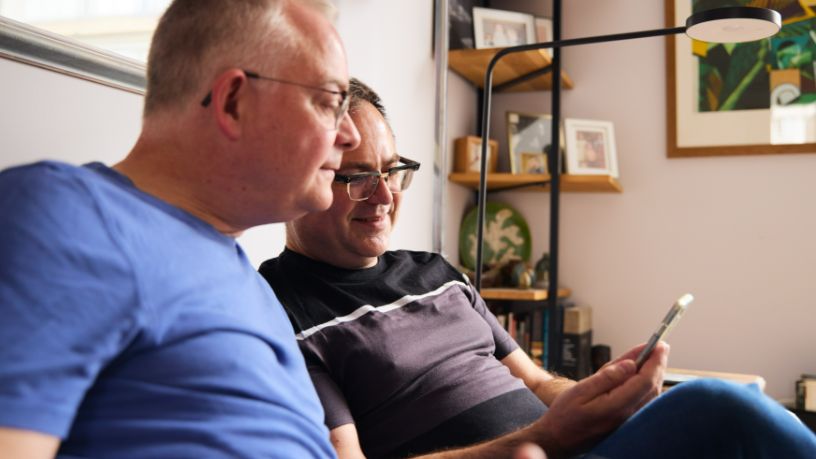 Two men look at a phone.