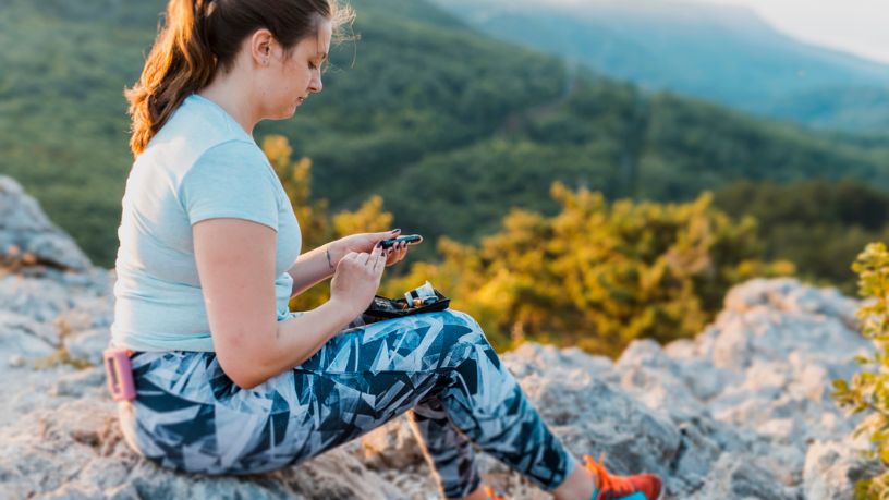Woman with diabetes checking her blood glucose whilst hiking.