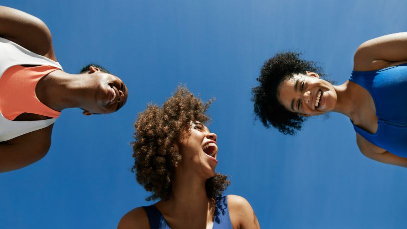 Three women smile down at the camera.