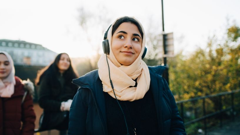 A woman walks while wearing headphones.
