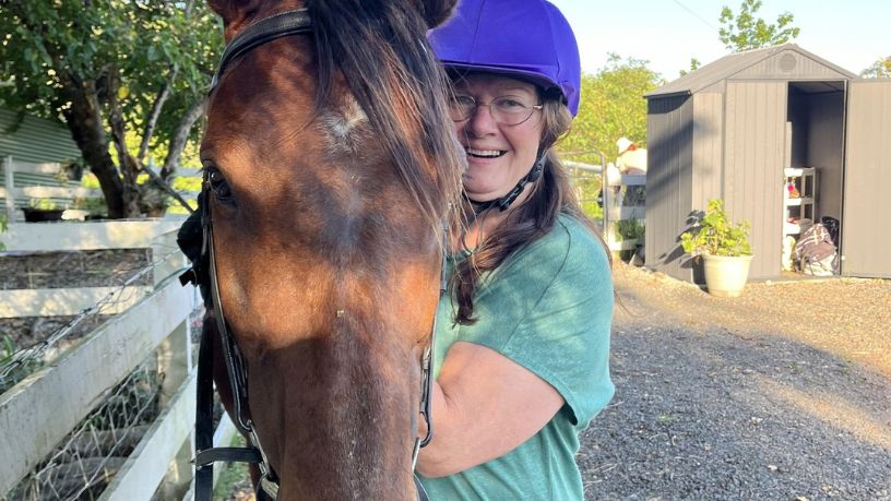 Eliza smiles at the camera with her horse Hunter.