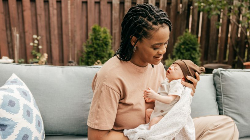 A woman holds her newborn outside.