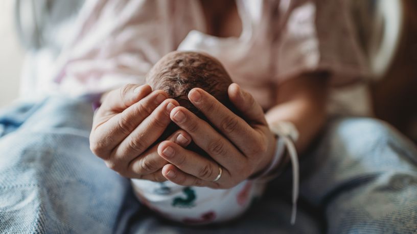 A person holds their newborn baby.