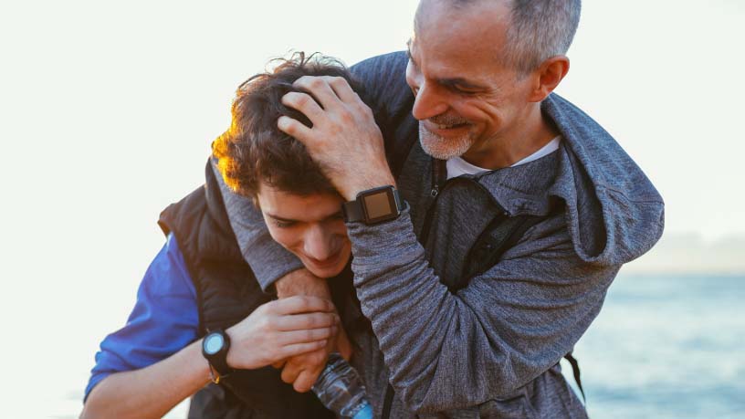 A father embraces his son in a playful headlock.