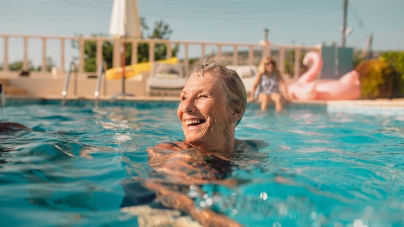 Older woman in swimming pool smiling.