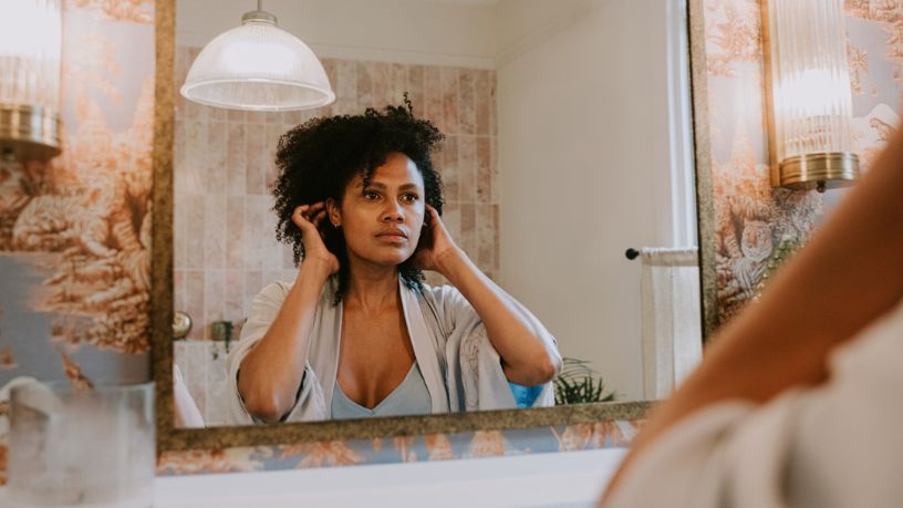 Woman standing in front of the mirror studying herself in her bathroom