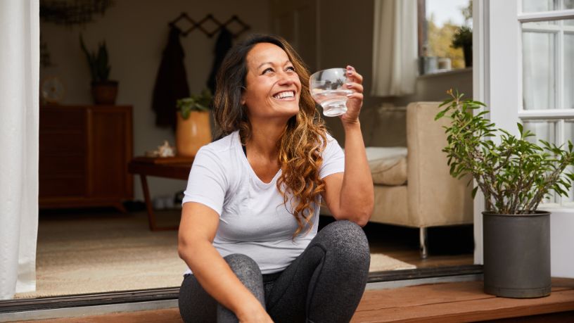 Lady sitting on her doorstep drinking water