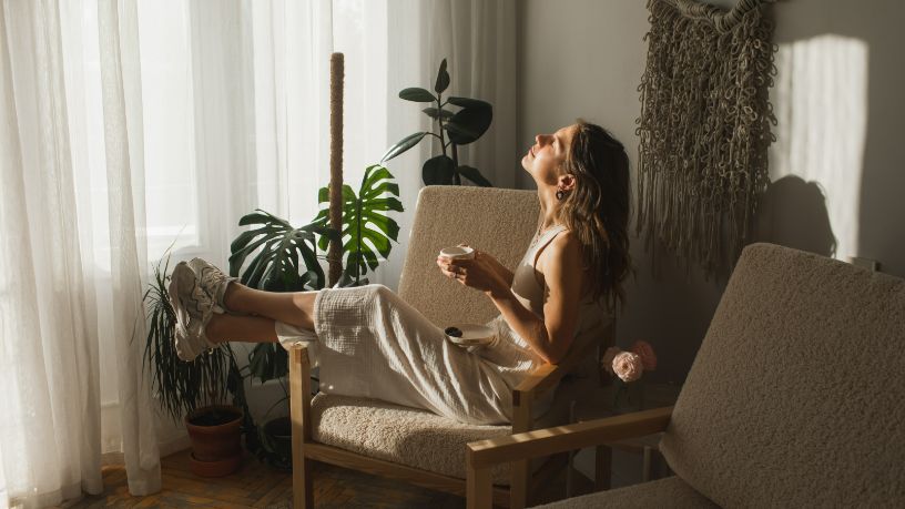 A woman relaxes on a couch with a cup of coffee.