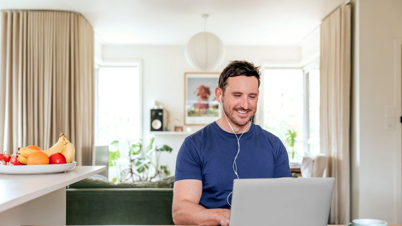 A man smiles as he speaks with someone on his laptop.