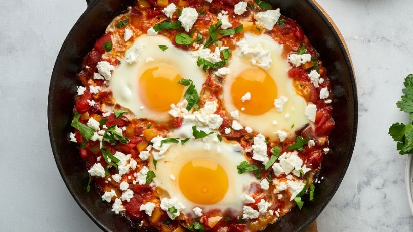A pan filled with shakshuka rests on a kitchen bench