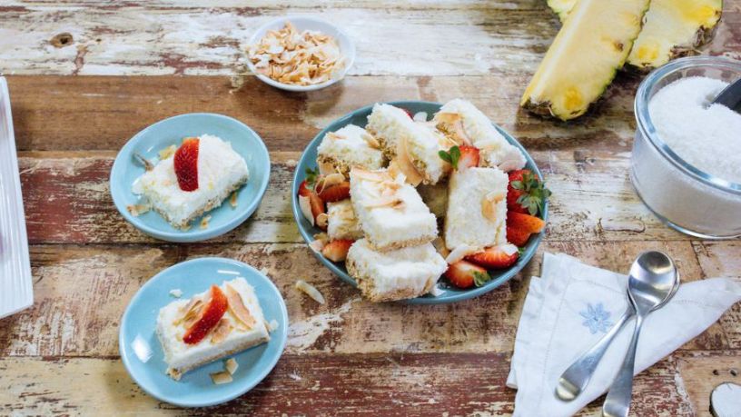 Square slices of coconut slices in light blue serving bowls on a wooden table