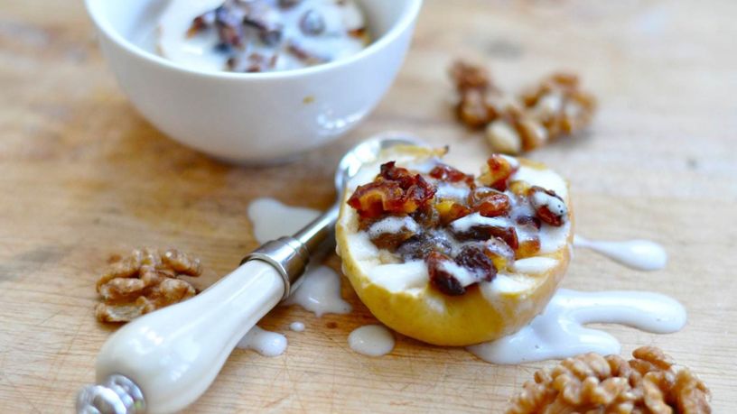 Half cooked apple with on table with a topping of walnuts, sultanas and splash of milk
