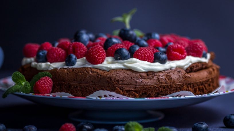 Chocolate cake topped with white frosting, blueberries and raspberries