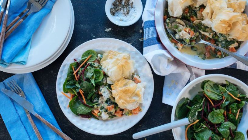 A dining table is filled with food, crockery and cutlery.