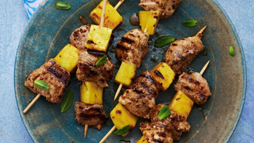 Five beef skewers lay on a plate