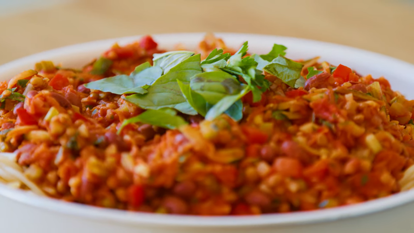 A bowl of lentil bolognaise topped with basil.