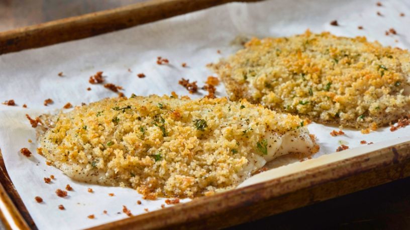 Two servings of quinoa crusted fish bake in an oven.