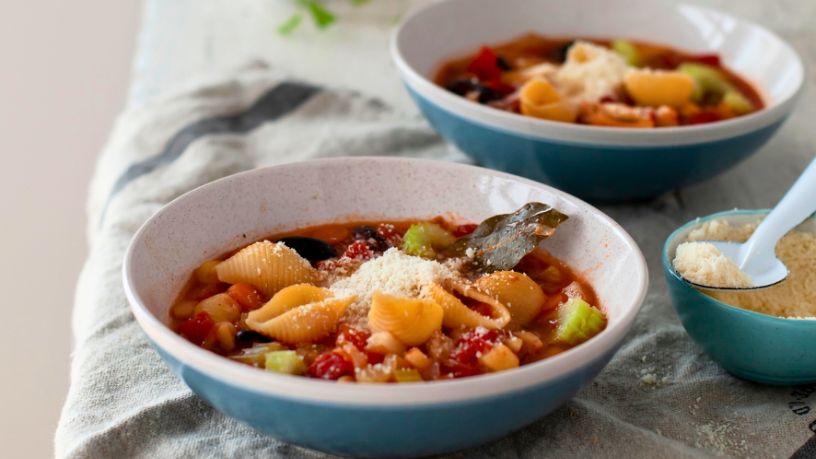 Two bowls of minestrone soup lay side by side.