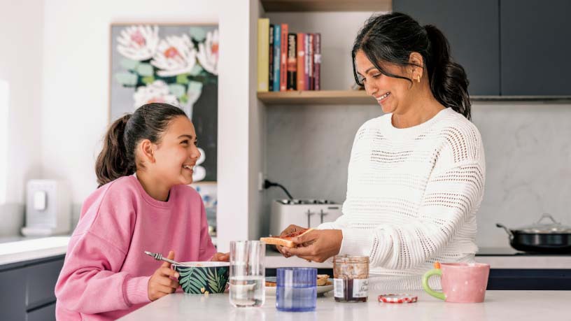 A woman and her daughter have breakfast together.