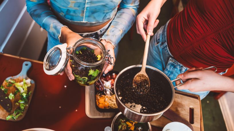 A woman making breakfast with fresh fruit, cereal and other healthy ingredients.