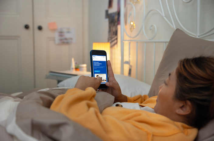 A person in bed browsing the Blua website on their phone.